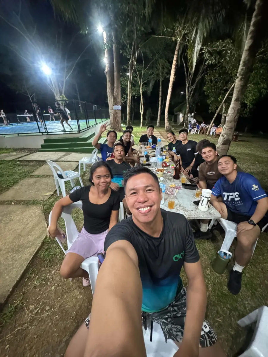 Players sitting around a long table beside the courts after an evening session